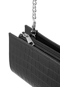 Clutch in pelle nera con finitura a effetto coccodrillo, chiusura con zip e tracolla in catena argentata. Presenta una texture liscia e una forma rettangolare.