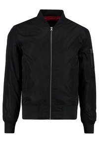 Veste bomber noire avec fermeture éclair à l’avant, poignets et ourlet côtelés, et doublure intérieure rouge. Comprend une poche zippée sur la manche gauche.