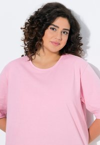 Rosa Baumwoll-T-Shirt mit kurzen Ärmeln, runden Ausschnitt und lockerer Passform. Weicher Stoff ohne sichtbare Muster oder Akzente.