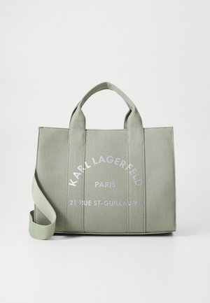Roheline kanvas kott, millel on kaks käepidet, reguleeritav õlarihm ja trükitud tekst: "KARL LAGERFELD PARIS 21 RUE ST-GUILLAUME."