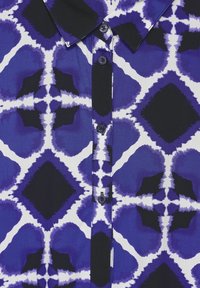 Chemise à boutons avec un motif abstrait bleu et blanc, dotée d'un col noir et d'une patte de boutonnage. Tissu lisse avec un léger brillant.