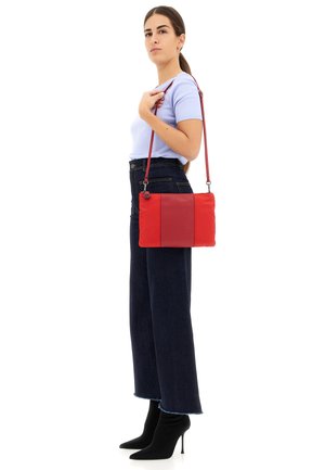 Borsa a tracolla rossa in pelle con finitura testurizzata, caratterizzata da una forma rettangolare e una tracolla regolabile, esposta su uno sfondo bianco.