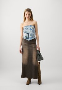 Top blu strapless con motivi floreali; lunga gonna marrone con gradiente; stivali al ginocchio beige; borsa nera con perline.