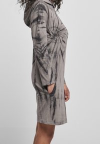 Sukienka z kapturem w wzór tie-dye w odcieniach szaro-czarnych, z długimi rękawami i bocznymi kieszeniami. Wykonana z miękkiego materiału o luźnym kroju.