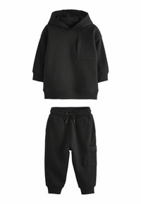 Hoodie noir avec poche avant et capuche réglable, associé à un jogger noir avec une taille élastique et une poche latérale.