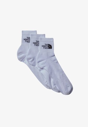 Trys poros baltų medvilninių kojinių su raukšlėmis. Kiekviena turi juodą "THE NORTH FACE" logotipą ir išlenktą kalnų grafiką.