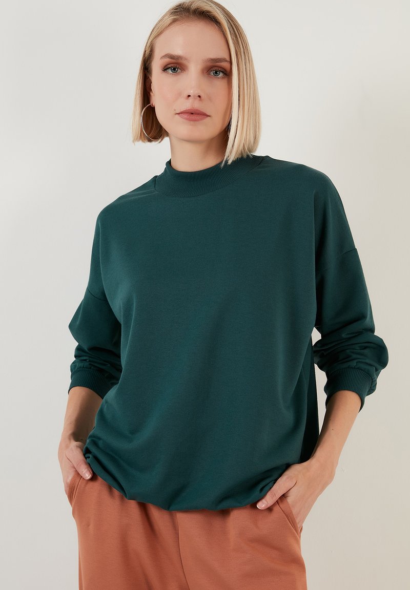 Felpa teal con collo alto e maniche lunghe, realizzata in tessuto morbido, con polsini a costine e vestibilità comoda.
