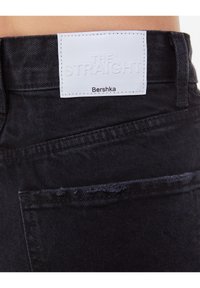 Černé džíny z denimu s rovný střih, s bílou nášivkou s nápisem "THE STRAIGHT" a "Bershka" na pase.