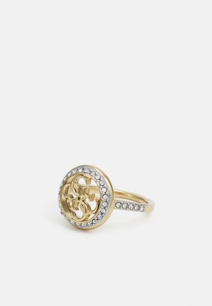 Guldring med et cirkulært design med sammenflettede bogstaver og en kant af små klare sten rundt om cirklen og på ringen.