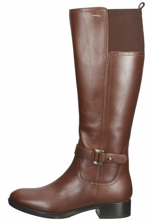 Botte en cuir brun hauteur genou avec un talon plat, dotée d'un panneau élastique marron et d'une sangle décorative à boucle sur le côté.