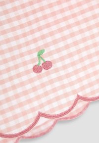 Rožinė gingham medžiaga su iškiliu kraštu, puošta raudonomis ir žaliomis siuvinėtomis vyšniomis, demonstruojanti tekstūruotą ir žaismingą dizainą.