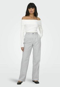 Off-shoulder vit ribbad topp kombinerad med vida randiga byxor. Setet har en åtsittande silhuett och en mjuk textur.