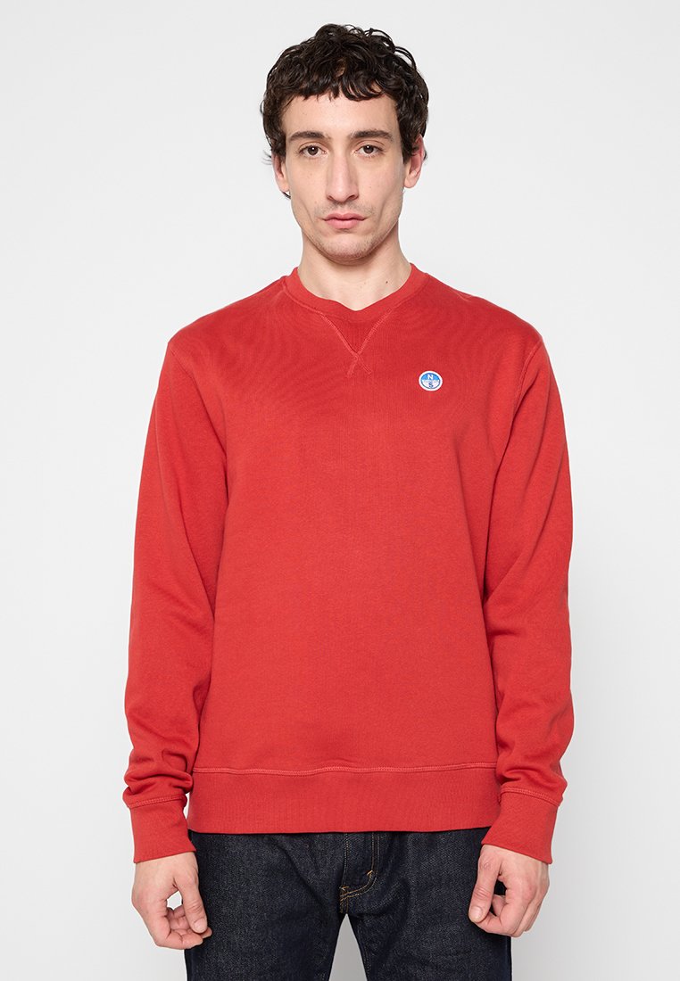 Felpa rossa in cotone con scollo e polsini a costine. Presenta un piccolo logo blu circolare sul petto. Vestibilità dritta e maniche lunghe.