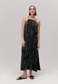 Sukienka maxi w ciemnoszarym kolorze z abstrakcyjnymi czarnymi wzorami. Ramiączka typu spaghetti, zwiewny krój i boczne rozcięcia, połączona z czarnymi klapkami.