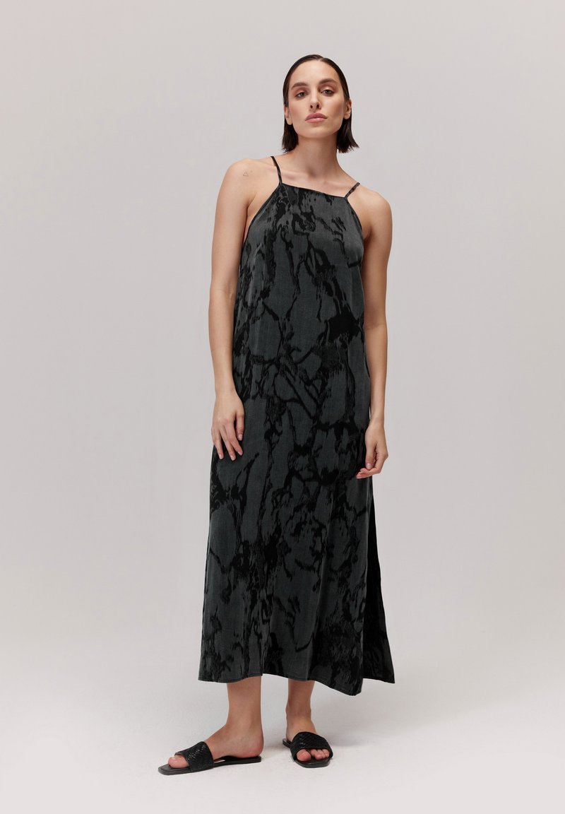 Sukienka maxi w ciemnoszarym kolorze z abstrakcyjnymi czarnymi wzorami. Ramiączka typu spaghetti, zwiewny krój i boczne rozcięcia, połączona z czarnymi klapkami.