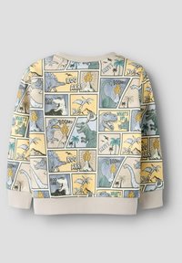 Genser laget av bomull, med et fargerikt trykk av en tegneserie-dinosaur fordelt på paneler. Fargene inkluderer gul, blå og grønn, med ribbestrikkede mansjetter.