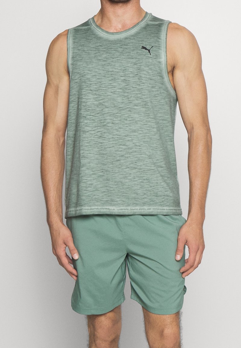 Zielony sportowy top bez rękawów z teksturowanym wykończeniem, z okrągłym dekoltem i małym czarnym logo. W zestawie z pasującymi zielonymi szortami.