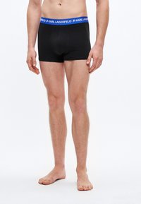 Μαύρα ανδρικά μποξεράκια με μπλε ζωνάκι μέσης που φέρει το λογότυπο "KARL LAGERFELD". Κατασκευασμένα από απαλό ύφασμα, εφαρμοστή γραμμή, μήκος πάνω από το γόνατο.