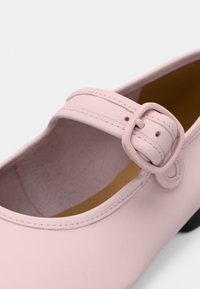 Ροζ παπούτσι Mary Jane με στρογγυλεμένη μύτη, πλευρικό λουράκι με αγκράφα και λείο φινίρισμα που μοιάζει με δέρμα, με αντίθετο κίτρινο εσωτερικό πάτο.