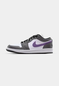 Nike žemų sportbačių modelis, pagamintas iš pilkos odos ir zomšos, baltas pirštų gaubtas, violetinės detalės, juodi raišteliai ir guminis padas su matomu protektoriumi.