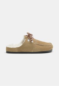 Bež moški čevelj iz semiša brez zavezovanja z belo podlogo iz volne, z vezanjem v slogu mokasina, vzorčastimi vezalkami in črnim gumijastim podplatom na preprostem ozadju.