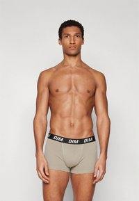 Beige boxershorts met een zwarte elastische tailleband met het "DIM"-logo. Ontworpen om nauwsluitend te passen, gemaakt van zacht, rekbaar materiaal.