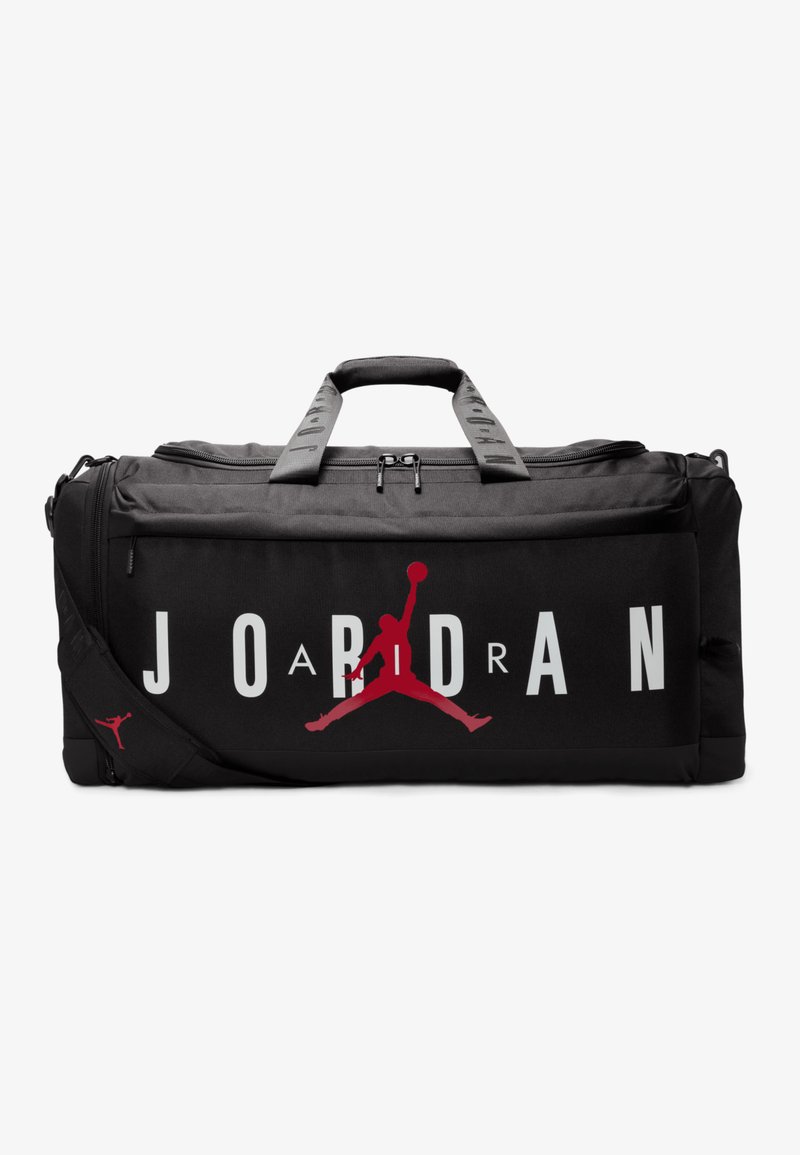 Sac de sport noir avec un grand texte blanc "JORDAN" et le logo Jumpman rouge, en tissu texturé, avec deux poignées et une bandoulière réglable.