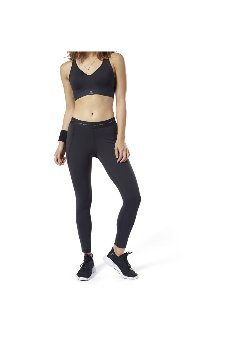 Czarny sportowy stanik oraz legginsy o wysokim stanie, wykonane z gładkiego, elastycznego materiału o dopasowanym kroju. Zawierają markowy pas w talii oraz akcenty na kostkach.