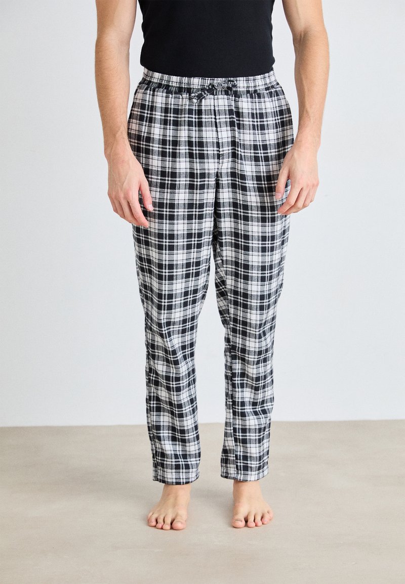 Pantalons de pyjama à carreaux noir et blanc avec une taille élastique et un cordon de serrage, offrant une coupe décontractée et un tissu léger.