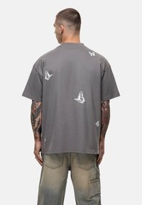 Grijze katoen t-shirt met een relaxte pasvorm, voorzien van witte vlinderafdrukken op de achterkant, ronde halslijn en korte mouwen.