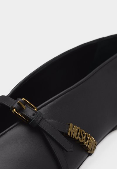 Chaussure plate en cuir noir avec boucle dorée et détail du logo Moschino sur la bride.