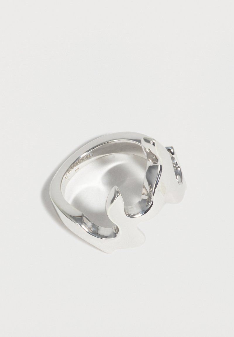 Ασημένιο ανοιχτό δαχτυλίδι σε σχήμα δύο δελφινιών που κοιτάζουν το ένα το άλλο, με γυαλιστερό φινίρισμα, χαραγμένο στο εσωτερικό με την επωνυμία και λεπτομέρειες καθαρότητας μετάλλου.