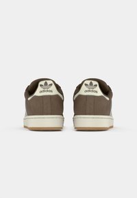 Sneakers in suede marrone con accenti bianchi, dotati di suola in gomma e logo in rilievo sul retro. Design classico a collo basso.