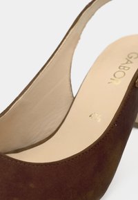 Γυναικείο καφετί σουέτ παπούτσι με λουράκι στο πίσω μέρος, εσωτερική επένδυση σε μπεζ χρώμα και ορατό μέγεθος 4½ τυπωμένο με χρυσά γράμματα στην εσωτερική σόλα.