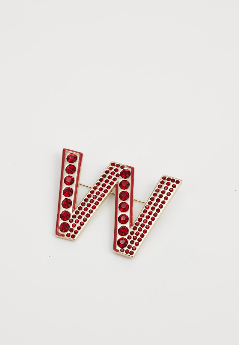 Broche ornée de pierres précieuses rouges en forme de lettre "W", avec de grandes et petites strass rouges sertis dans un cadre en métal doré.