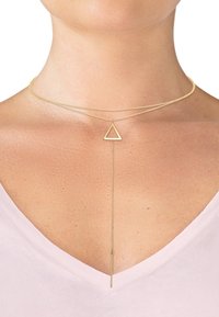 Collier doré en couches avec un pendentif triangulaire et une goutte de chaîne verticale. Texture lisse, design minimaliste et structure délicate.