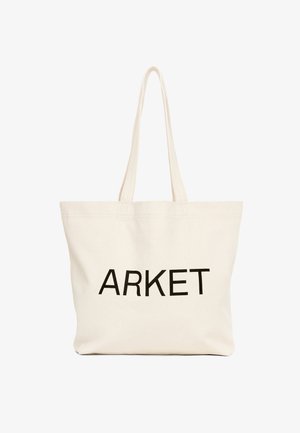 Borsa tote in tela beige con manici lunghi e scritta nera "ARKET" stampata sul davanti.