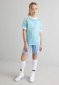 Lyseblå kortermet jersey med abstrakt mønster, hvite detaljer, matchende shorts og hvite sokker. Har Adidas-logo og striper.