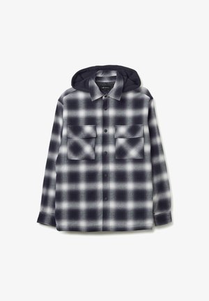 Camicia a scacchi in nero, bianco e grigio con cappuccio. Presenta chiusure a bottone, due tasche sul petto e una vestibilità ampia. Texture morbida.