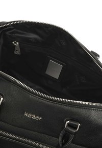 Fekete bőrtáska, textúrált külső kialakítással, ezüst színű hardverrel és cipzáras belső zsebével, logócímkével a szövetbélésen.