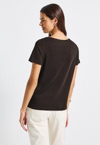 Černé tričko s krátkým rukávem a kulatým výstřihem, vyrobené z měkké látky. Zadní část má jednoduchý, nezdobený design.