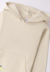 Felpa con cappuccio beige realizzata in tessuto morbido, con tasca frontale e un piccolo dettaglio grafico sul lato sinistro in basso.