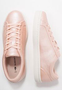 Baskets en cuir rose avec semelles en caoutchouc blanc, bout arrondi, texture lisse et design à lacets. Comprend un logo sur la semelle intérieure.