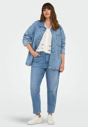 Blaues Denim-Hemdjacke über einem weißen Spitzenoberteil, kombiniert mit hellblauen Jeans und weißen Sneakers. Lässiges Outfit mit entspanntem Schnitt.