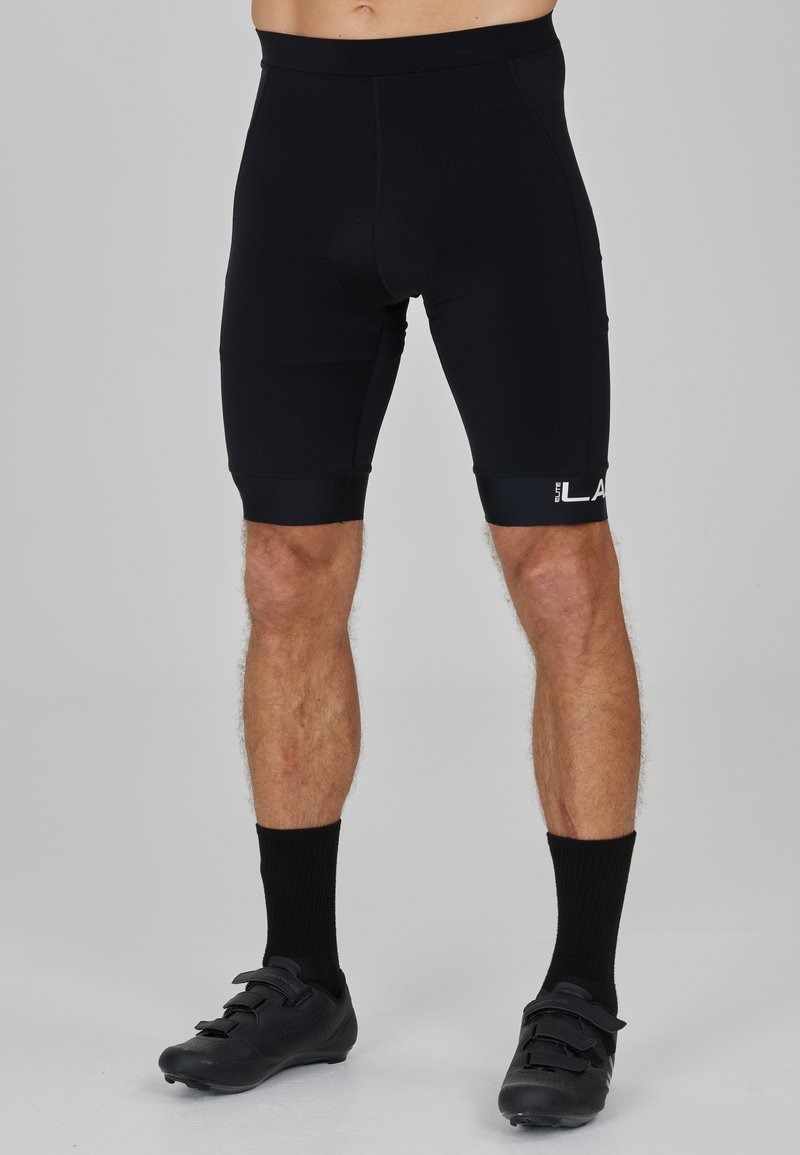Pantaloni sportivi neri con un design aderente, vita elastica e dettaglio del logo sulla gamba sinistra. Texture liscia, lunghezza a metà coscia.