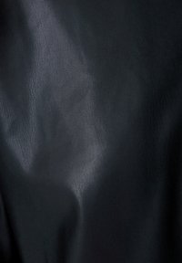 Černá koženka s hladkým povrchem a mírným leskem. Obsahuje subtilní zrnitý vzor a záhyby, což vytváří dimenzionální vzhled.