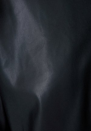 Černá koženka s hladkým povrchem a mírným leskem. Obsahuje subtilní zrnitý vzor a záhyby, což vytváří dimenzionální vzhled.