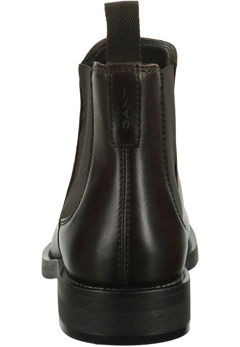 Bottines en cuir brun foncé avec des panneaux latéraux élastiques noirs, une languette à l'arrière, des coutures détaillées et une semelle basse noire.