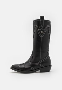 Zwarte leren cowboylaars met witte contraststiksels, puntige neus en een lage blokhak. Bevat decoratieve stiksels en een trekstrip.