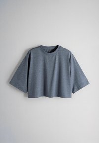 Tricou gri, cu mâneci scurte, tăiat scurt, cu decolteu rotund, așezat plat pe un fundal gri deschis.